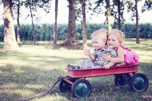 young boy and girl riding in a red wagon