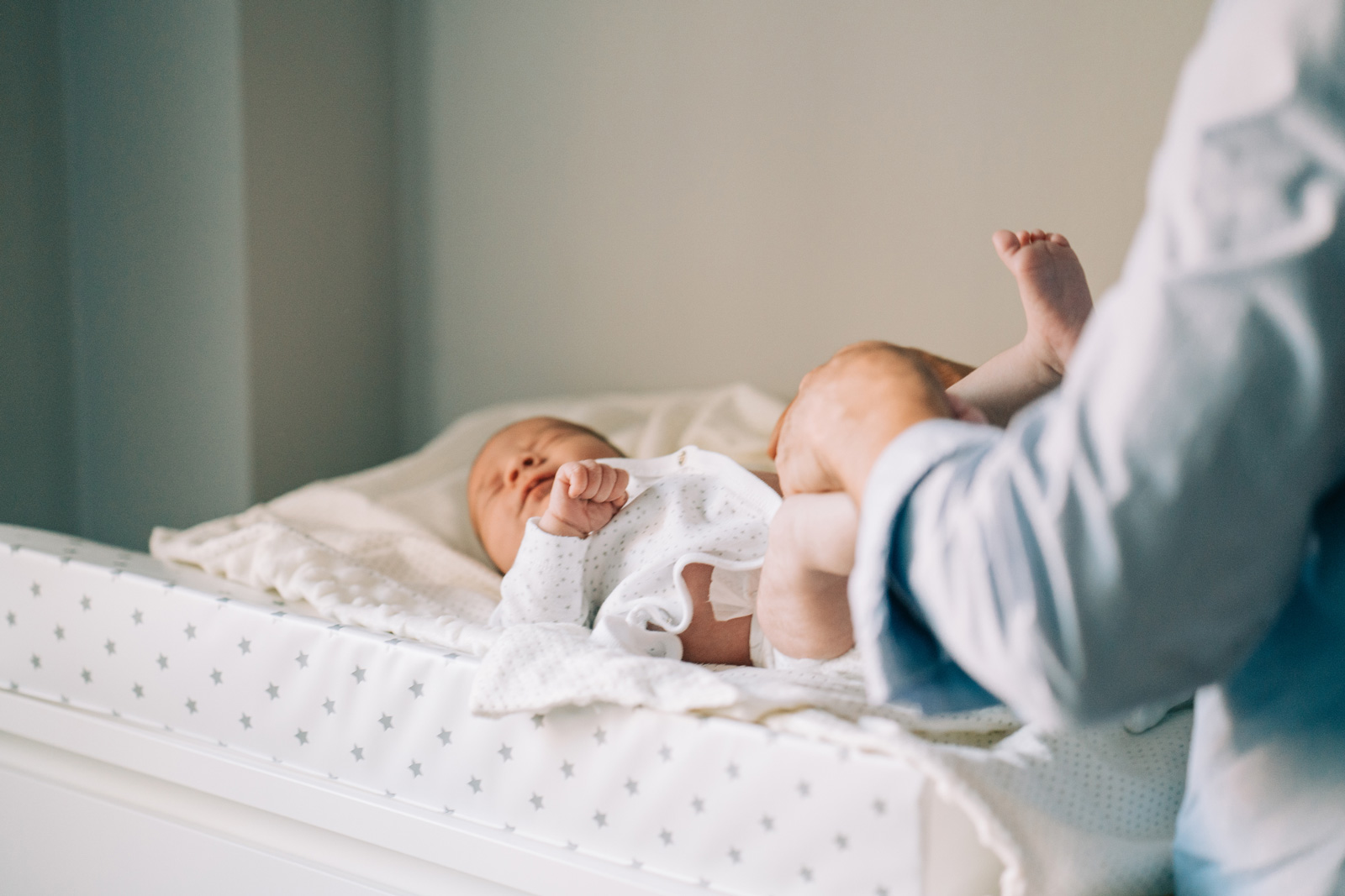 Parent changes newborn's diaper on changing pad