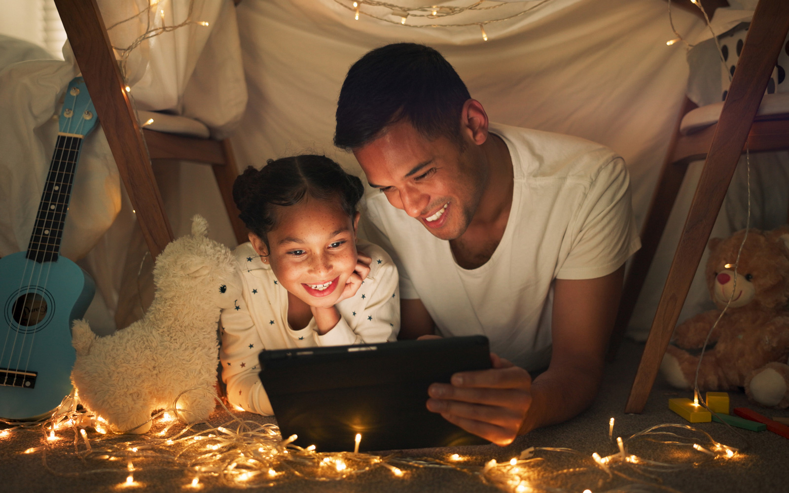 Dad and daughter read in a fort