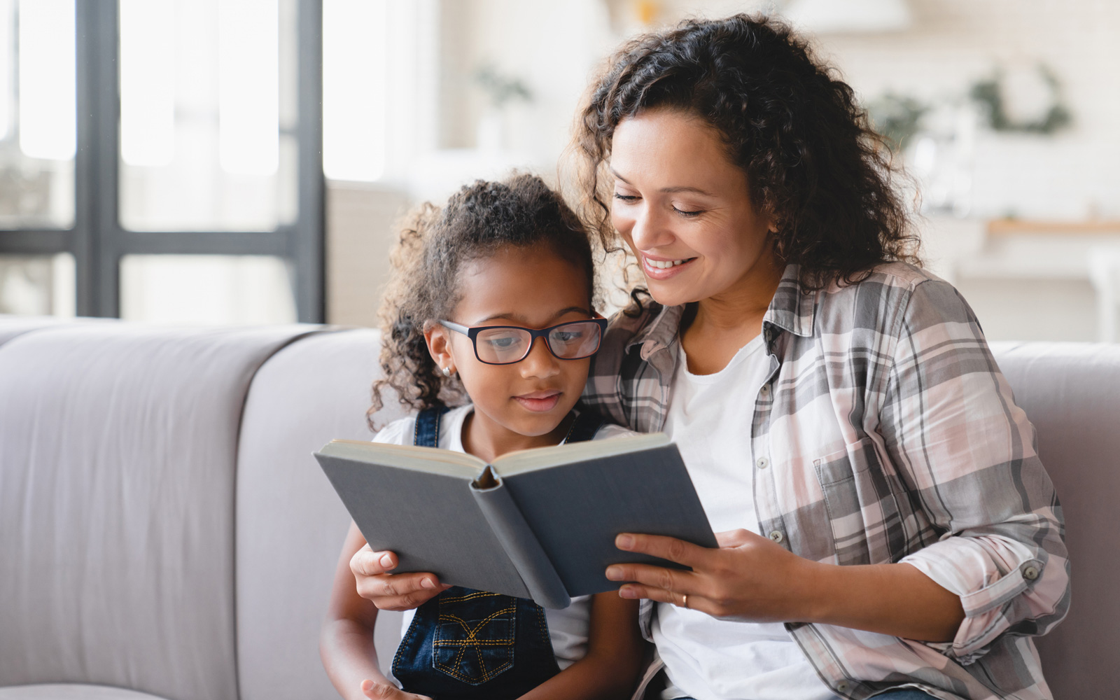 Mom reading with her daughter on the couch